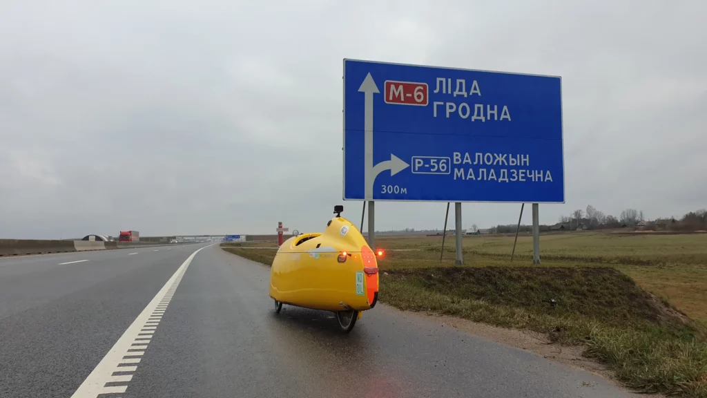 Quest velomobile standing in front of a traffic sign