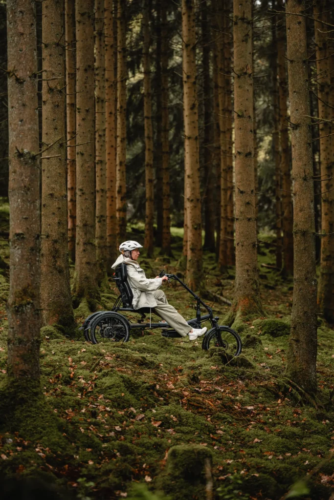 senior riding through the woods on her recumbent delta trike